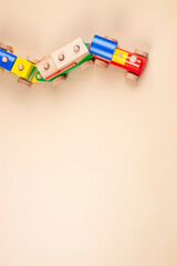 Wooden toy train with multi colored blocks on pastel beige background. Top view