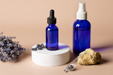 Lavender cosmetics products in blue glass bottles on beige background with bunch of dry lavender. SPA organic beauty concept. packaging for branding mockup. copy space