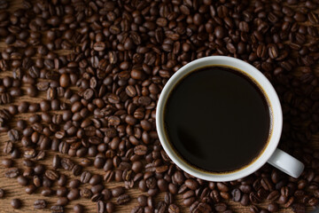 Black coffee and coffee beans roasted on wooden background,Top view,copy space.