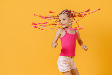 Stylish girl with pink dreadlocks and posing on a yellow backgro