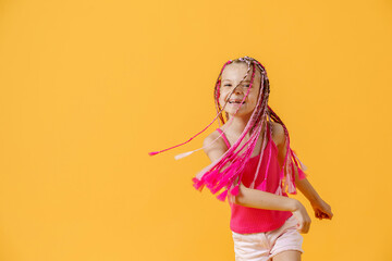 Stylish girl with pink dreadlocks and posing on a yellow backgro