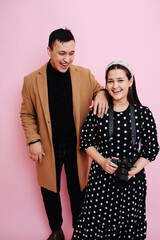 Carefree happy young couple posing for a photo over pink background.