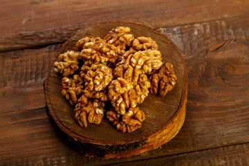 Walnuts are scattered on a round board on a wooden table.