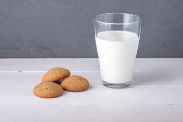 three oatmeal cookies and a glass of yogurt on the table