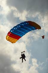 Skydivers under the parachute canopy while jumping in tandem, close-up.