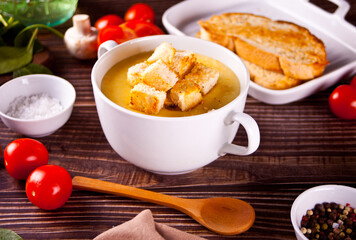 Cheese or onion cream soup with toasts bread in a white bowl