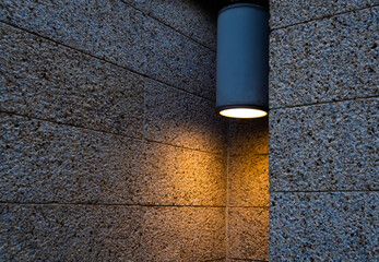 Moody lamp on a textured brick wall in the evening.