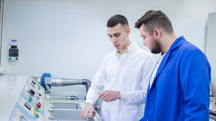 Industrial designer and technician examining equipment in factory