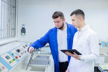 Industrial designer and technician examining equipment in factory