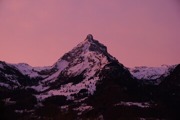 Rosaroter Himmel über spitzem Berggipfel