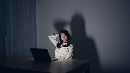 暗い部屋でパソコン作業をする女性