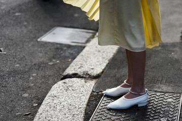 Detail of a fashionable outfit – woman wearing white shoes and yellow skirt