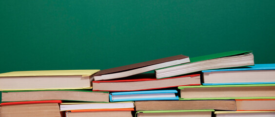Composition with vintage old hardback books, diary, fanned pages on wooden deck table and colored background. Books stacking. Back to school. Copy Space. Education background.