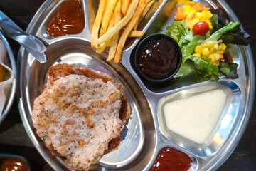 Pork steak with fries and vegetables on the food tray