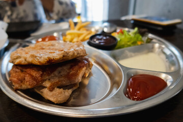 Pork steak with fries and vegetables on the food tray
