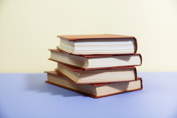 Composition with vintage old hardback books, diary, fanned pages on wooden deck table and colored background. Books stacking. Back to school. Copy Space. Education background.