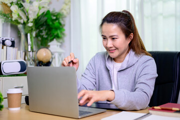 Asian businesswoman online working at home. Thai woman lifestyle in living room. Social distancing...