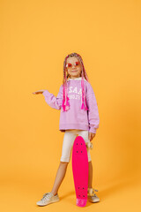 Active young girl in pink shirt and white shorts holding skatebo