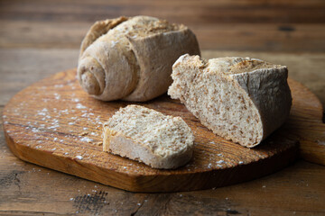 Homemade italian bread on a wooden cutting board with white flour.