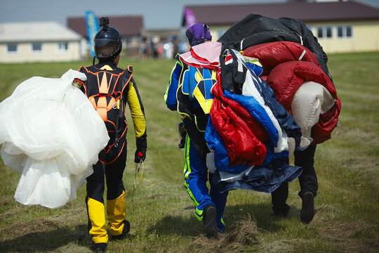 The team of skydivers going on the airfield after landing with a parachute, rear view close-up.