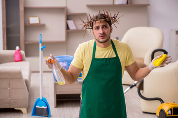 Young male contractor wearing prickly wreath on head cleaning th