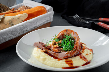 Baked beef tongue with mashed potatoes and sauce on a white plate. British cuisine