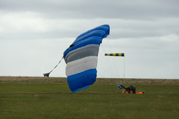 Skydiver tries to get on his feet after a failed landing with parachute in windy weather.