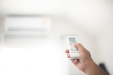 Man hand using a remote control for Air condition. control the temperature of the air condition at 25 degree celsius. Balance the air asmosphere. Energy saving concept