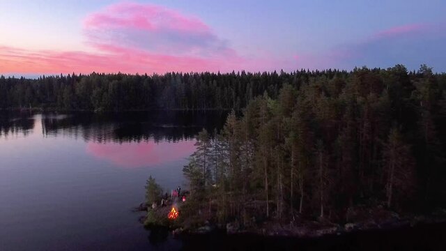 Midsummer bonfire on island in Finland. Beautiful sunset over forest and reflecting on water.