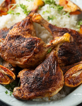 Slow cooked aromatic duck legs with basmati rice and side salad served with orange wedges.