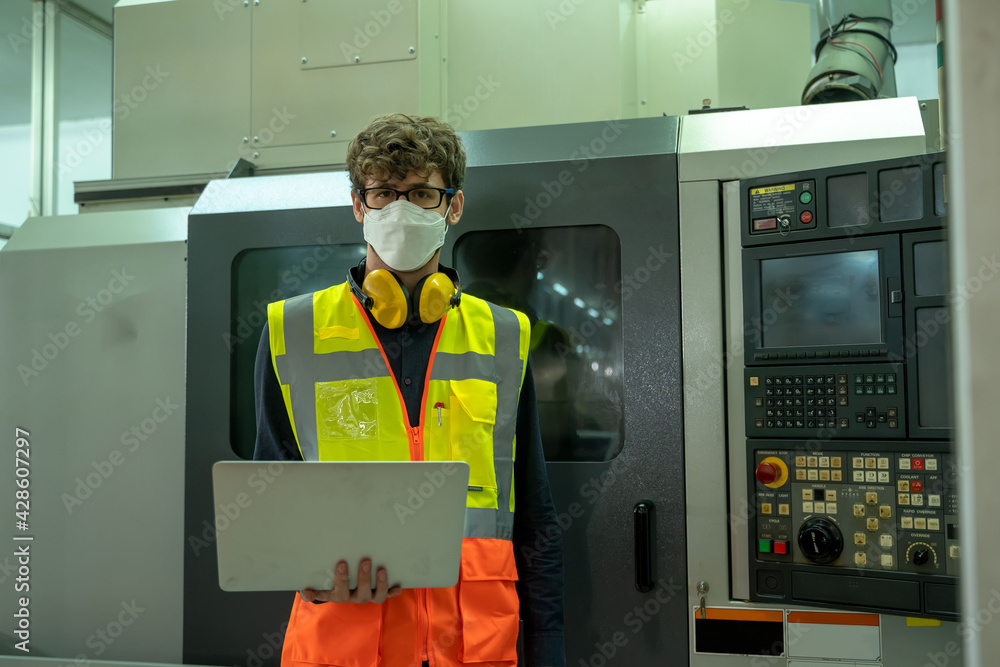 Poster professional technicians wears face mask standing and holding laptop with confident working at facto