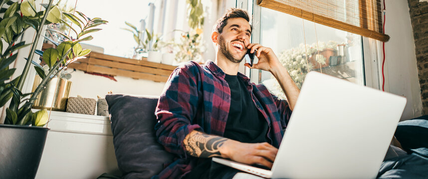 Young Man With Laptop And Smartphone At Home. Freelancer. Concept Of Remote Work Or Study.