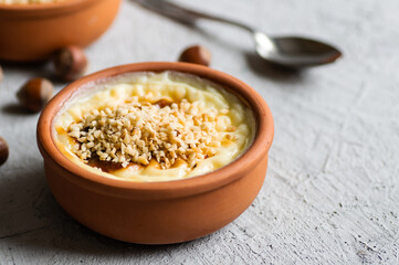 Baked rice pudding turkish milky dessert sutlac in casserole with cinnamon sticks and chopped hazelnuts