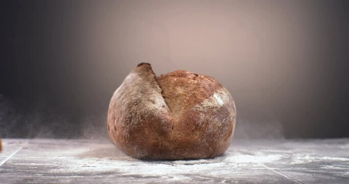 SUPER SLOW MOTION Freshly baked loaf of bread falling on a table covered with flour. Shot with high speed camera at 420 FPS