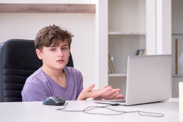 Schoolboy playing computer games at home