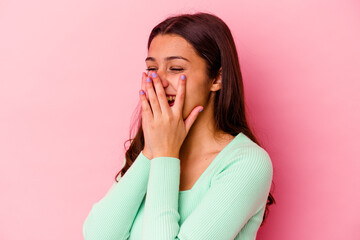 Young Indian woman isolated on pink background laughing about something, covering mouth with hands.