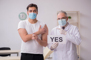 Young male patient visiting old male doctor in vaccination conce