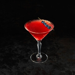 Cosmopolitan cocktail in nice red color in front of a black background