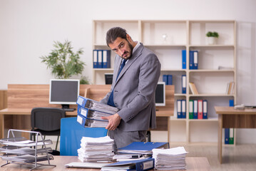 Young businessman employee unhappy with excessive work in the of