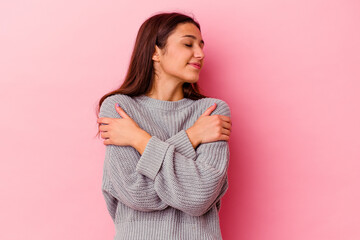 Young Indian woman isolated on pink background hugs, smiling carefree and happy.