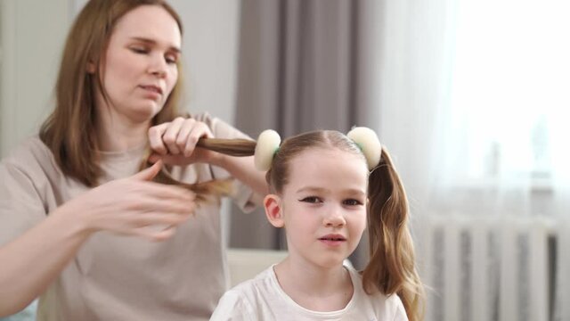 Mom makes a hairstyle her daughter, hurry, it turns out not immediately. preparing the child for the performance on stage. eye makeup.