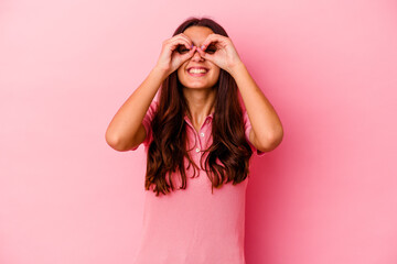 Young Indian woman isolated on pink background showing okay sign over eyes