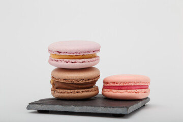 Colorful macaroons on grey mat on white background. Sweet bakery, copy space.