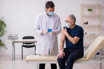 Old male patient visiting young male doctor in vaccination conce