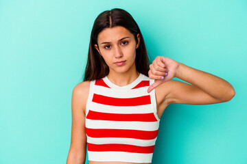 Young Indian woman isolated on blue background showing a dislike gesture, thumbs down. Disagreement...