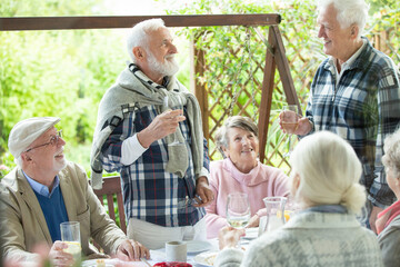 Happy group of retired friends having fun during birthday party at the garden