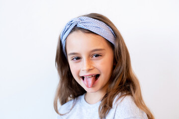 Playful kid portrait. Fun childhood. Positive lifestyle. Amused joyful happy cute smiling little girl teasing sticking tongue out isolated on white background.