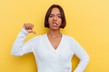 Young mixed race woman isolated on yellow background showing a dislike gesture, thumbs down....