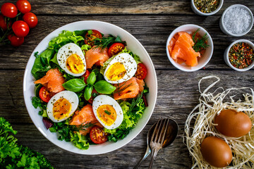 Salmon salad - smoked salmon hard boiled eggs and green vegetables on wooden table
