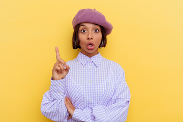 Young mixed race woman wearing a beret isolated on yellow background having some great idea, concept of creativity.